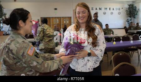 Us-Armee Sgt. Zahyra Yates, eine Armee-reservesoldat zugewiesen, um die Armee finden Cyber Operations Group (ARCOG), 335.- Signal (Theater), Geschenke Blumen an ein Familienmitglied während einer Willkommen Home Krieger Zeremonie für Soldaten aus der ARCOG North Capital Region Cyber Protection Center, 2. April in Fort Meade, Maryland eingesetzt. Die NCRCPC Soldaten in Kuwait eingesetzt cyber Training und Missionen zur Unterstützung der US-Army Central Command. Stockfoto