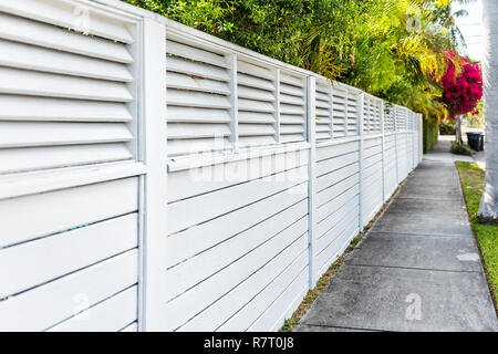 Weißen Zaun und rote oder rosafarbene Bougainvillea Blüten in Florida Keys oder Miami, grüne Pflanzen Landschaftsbau angelegten Gehweg Straße Straße Haus während der Summ Stockfoto