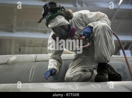 Arabischen Golf (29. März 2017) Aviation strukturellen Mechaniker 3. Klasse Brett Lee, der "Ragin' Bulls" von Strike Fighter Squadron (VFA) 37, sands Korrosion aus einer F/A-18C Hornet an Bord der Flugzeugträger USS George H.W. zugeordnet Bush (CVN 77) (GHWB). GHWB ist in den USA der 5. Flotte Bereich für Maßnahmen zur Erhöhung der Sicherheit des Seeverkehrs auf die Verbündeten und Partnern zu beruhigen bereitgestellt, und der Freiheit der Schiffahrt und des freien Handels in der Region erhalten. Stockfoto