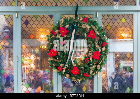 Weihnachten Kranz und Spiegelungen im Fenster auf der Efeu in Winchester Weihnachtsmarkt, Winchester, Hampshire, UK im Dezember Stockfoto