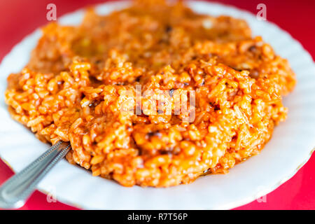 Nahaufnahme von frischen leuchtend rote Tomatensauce paella gebratene Paprika Reis Chili auf Platte in Sauce, Normal fettig glänzenden Körnern im Restaurant auf weiße Platte Stockfoto