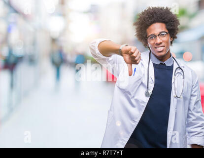 Afro-amerikanische Arzt Mann über isolierte Hintergrund unzufrieden und wütend, Ablehnung und negativ mit Daumen nach unten Geste. Schlechter Ausdruck. Stockfoto