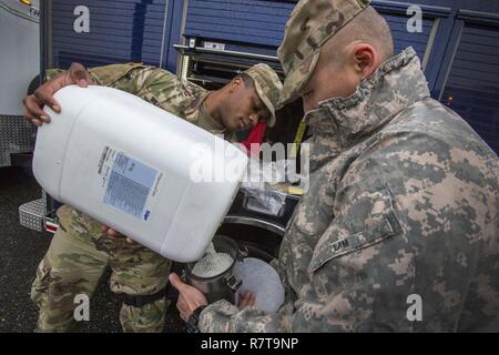 Übersicht Teammitglieder Sgt. Koran Williams, Links, und Staff Sgt. Nicky Lam, beide mit 21 Waffen der New Jersey National Guard von Mass Destruction-Civil Support Team, füllen BG4 rebreather Einheiten mit Natronkalk, die entfernt Kohlendioxid, bei einer gemeinsamen Übung mit den Mitgliedern der Monmouth County Hazmat Team in Fort Monmouth, New Jersey, April 6, 2017. Das 21 WMD-CST ist eine gemeinsame Einheit aus New Jersey National Guard Soldaten und Piloten, deren Aufgabe es ist, die zivilen Autoritäten durch die Identifizierung von chemischen, biologischen, radiologischen und nuklearen Stoffen entweder in man-made oder nat Stockfoto