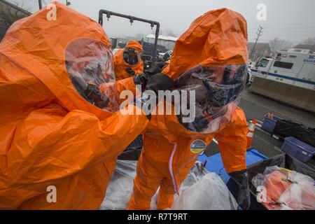 Staff Sgt. Kenneth Williams, Links, unterstützt Sgt. Koran Williams, beide mit 21 Waffen der New Jersey National Guard von Mass Destruction-Civil Support Team, in der sein Niveau ein Schutzanzug bei einer gemeinsamen Übung mit den Mitgliedern der Monmouth County Hazmat Team in Fort Monmouth, New Jersey, April 6, 2017. Das 21 WMD-CST ist eine gemeinsame Einheit aus New Jersey National Guard Soldaten und Piloten, deren Aufgabe es ist, die zivilen Autoritäten durch die Identifizierung von chemischen, biologischen, radiologischen und nuklearen Stoffen entweder in man-made oder Naturkatastrophen. (New Jersey National Guard Stockfoto