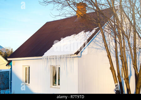 Das kleine Haus mit Eiszapfen. Wohnhaus an einem Wintertag, ein wenig Schnee auf dem Dach in der Sonne, horizontale Schuß Stockfoto