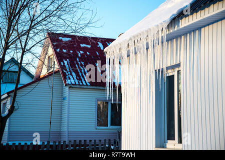 Das kleine Haus mit Eiszapfen. Wohnhaus an einem Wintertag, ein wenig Schnee auf dem Dach in der Sonne, horizontale Schuß Stockfoto