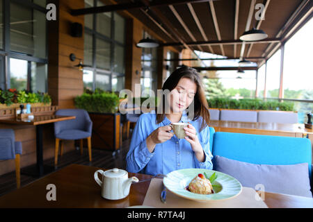 Europäische Mädchen trinken Kaffee im Restaurant und essen Kuchen. Stockfoto