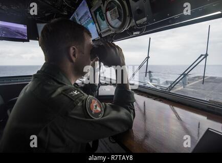 SOUTH CHINA SEA (5. April 2017) Kapitän Mark A. Melson, kommandierender Offizier der Amphibisches Schiff USS Makin Island (LL 8), scannt den Horizont der Pilot House. Makin Island ist das Flaggschiff der Amphibischen bereit, der Betrieb ist in der Indo-Asia-pazifischen Region amphibische Fähigkeit mit regionalen Partnern zu verbessern und als gebrauchsfertige Response Force für jede Art der Kontingenz zu dienen. Stockfoto