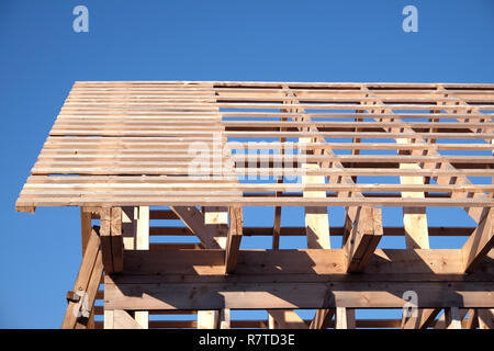 Prozess der Holz- karkasse Haus Montage ubder klar wolkenlosen blauen Himmel von der Seite. Holz haus Bau Stockfoto