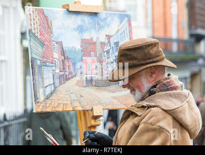 Künstler Malerei Straße an der High Street in Winchester, Hampshire, UK im Dezember Stockfoto