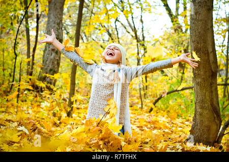 Kleines Mädchen werfen Blätter im Herbst Stockfoto