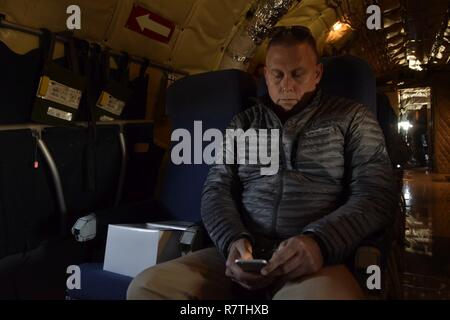 David Brown, Mitglied der Tinker Air Force Base Honorary Commander's 2017 Klasse sieht auf Fotos, die er auf seinem Mobiltelefon an Bord einer KC-135 R Stratotanker der 507th Air Refuelling Flügel, Air Force Reserve Command, während eines lokalen Ausbildung Flug am 6. April 2017 getroffen hat, von Tinker Air Force Base, Oklahoma. Die Ehrenamtlichen Commander's über Mission der KC-135 Stratotanker R's während der Luftbetankung Mission mit F-16 Fighting Falcons der 138 Fighter Wing, Oklahoma Air National Guard gelernt. Stockfoto