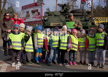 Sgt. Nathan Joachim (R), truppführer, von Ghost Truppe, 2d, 2d-Cavalry Regiment, US-Army, posiert für ein Foto mit Kindern von Unter den Eichen Vorschule während einer Battle Group Polen Fahrzeuge Static Display in Wesola, Polen 29. März 2017. Die Kinder präsentierten die Soldaten ein Buch gemacht, das mit gezeichnete Bilder und gut gefüllt ist. Die Veranstaltung ist eine Station auf dem Weg nach Orzysz, Polen, wo die Soldaten in eine verbesserte Zukunft Gegenwart teilnehmen werden. Stockfoto