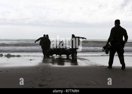 Marines mit Hotel Company, 2 Raider Bataillon, Marine Corps Forces Special Operations Command (MARSOC) in Camp Lejeune in North Carolina, tragen eine starre Hülle Zodiac Schlauchboot in die Brandung am Onslow Strand auf Base, 28. März 2017. Ein 45-Fuß-Antwort Boat-Medium Crew von der Coast Guard Station Wrightsville Beach, North Carolina, sofern Waterside unterstützen, während die Marines mehrfach vom Hubschrauber gesprungen und pilotiert Sternzeichen Boote während einer Übung. Stockfoto