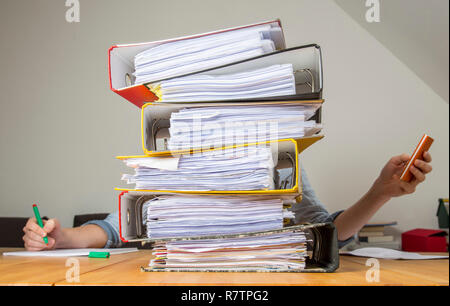 Frau an einem Schreibtisch hinter einem Stapel Akten arbeiten Stockfoto