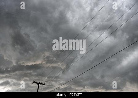 Strommast und Stromleitungen, Infrastruktur zur Stromverteilung mit Wolken und stürmischer Himmel in Wyoming, USA Stockfoto