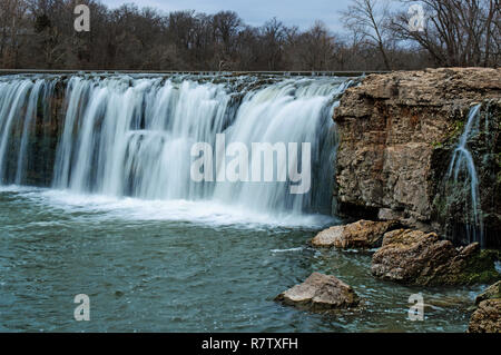 Wasserfall unter Felsbrocken auf einen warmen Winter Tag bildet eine malerische Aussicht Stockfoto