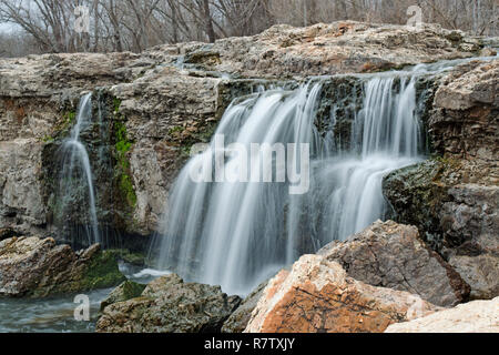 Wasserfall unter Felsbrocken auf einen warmen Winter Tag bildet eine malerische Aussicht Stockfoto