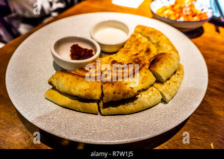 Chinesische Xinjiang Uyghur Naan Brot auf einem Teller mit Sauerrahm und Chili Stockfoto