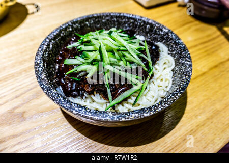 Koreanische Jajangmyeon Teller serviert in einem Stein Schüssel garniert mit Gurke Stockfoto