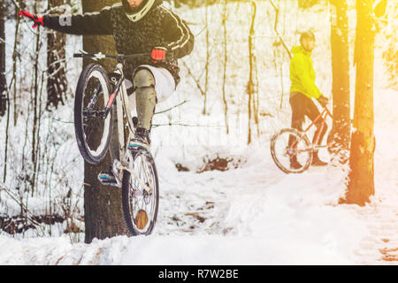 Bike Reiter fliegt durch die Luft. Mountainbiken auf Wanderwegen in einem verschneiten Wald. Extreme Winter Sport. Stockfoto