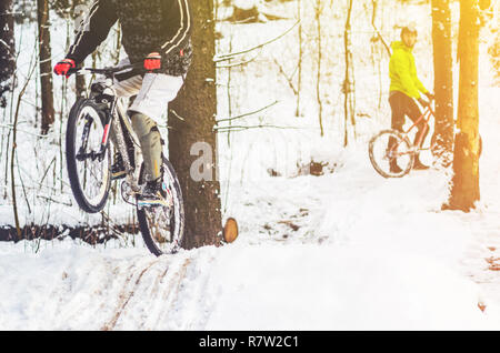 Bike Reiter fliegt durch die Luft. Mountainbiken auf Wanderwegen in einem verschneiten Wald. Extreme Winter Sport. Stockfoto