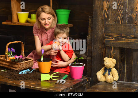 Spritzen Konzept. Mutter und Sohn Sprühwasser auf Topfpflanze. Mutter und Kind spritzen Frühling Blumen im Topf. Spritzen Wasserflaschen oder Feldspritze Stockfoto