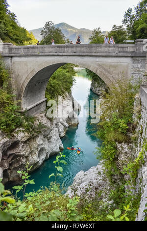 Napoleonbrücke bei Kobarid in den slowenischen Alpen. Leute, die im wunderschönen türkisfarbenen Wasser des Soca-Flusses Kajak fahren. Stockfoto