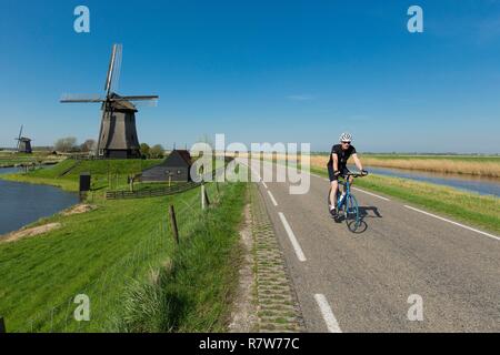 Niederlande, Südholland Provinz, Region Leeghwater, De Rijp, Radfahrer und Windmühle auf Schermer Polder Stockfoto