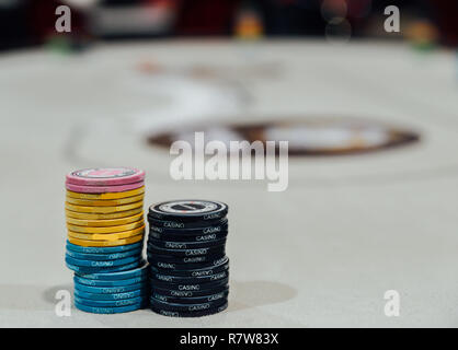 Zwei Stapel von Poker chips mit Defokussierten Poker Tisch im Hintergrund. Stockfoto