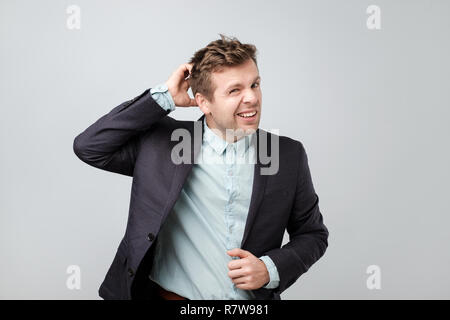 Verwirrt reifer Mann im Anzug seinen Kopf kratzen Stockfoto