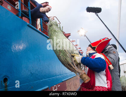 12. Dezember 2018, Mecklenburg-Vorpommern, Rostock: 12.12.2018, Mecklenburg-Vorpommern, Rostock: der Seeleute ist diakon Folkert J. Jansen Hände über einen Weihnachtsbaum aus dem Fischerboot "Pasewalk", um Kapitän Knut der Motorschiff "Lore Prahm" in der Rostocker Seehafen. Die kostenlose Verteilung von Weihnachtsbäumen für die Besatzungen der Schiffe im Hafen ist ein langjähriger Weihnachten Tradition. Foto: Frank Hormann/dpa Stockfoto