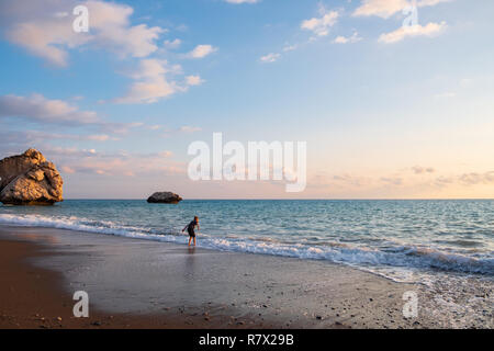 Eine barfüßige Junge spielt an der Strand von Petra tou Romiou Felsen, in Paphos, Zypern. Der Strand ist der Geburtsort der Aphrodite in der Griechischen my angesehen Stockfoto