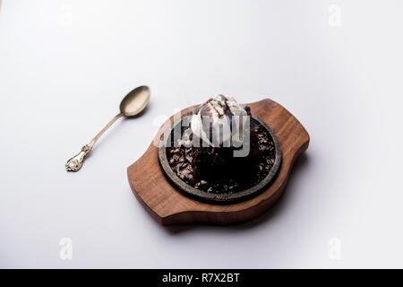 Sizzling Chocolate Brownie ist eine Süßspeise, die mit Kugel Eis-Creme auf der Oberseite mit einem großzügigen Gießen der geschmolzene Schokolade serviert. Server heiß. wählen Stockfoto