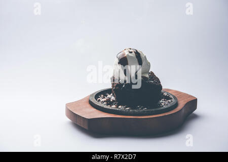 Sizzling Chocolate Brownie ist eine Süßspeise, die mit Kugel Eis-Creme auf der Oberseite mit einem großzügigen Gießen der geschmolzene Schokolade serviert. Server heiß. wählen Stockfoto