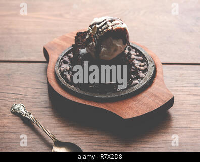 Sizzling Chocolate Brownie ist eine Süßspeise, die mit Kugel Eis-Creme auf der Oberseite mit einem großzügigen Gießen der geschmolzene Schokolade serviert. Server heiß. wählen Stockfoto
