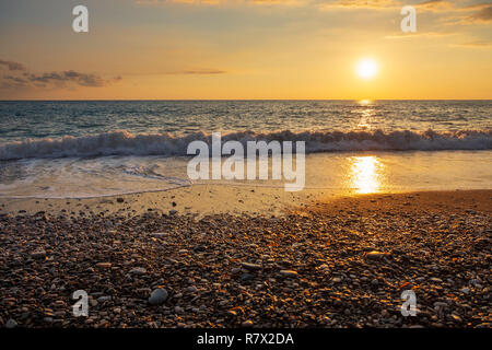 Schöne Aussicht auf den Sonnenuntergang von brechenden Wellen bei Petra tou Romiou Beach in Paphos, Zypern. Es gilt als Geburtsort der Aphrodite ist in der griechischen Mythologie. Stockfoto