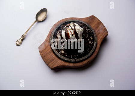 Sizzling Chocolate Brownie ist eine Süßspeise, die mit Kugel Eis-Creme auf der Oberseite mit einem großzügigen Gießen der geschmolzene Schokolade serviert. Server heiß. wählen Stockfoto