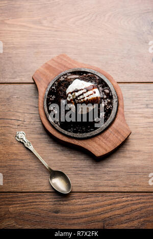 Sizzling Chocolate Brownie ist eine Süßspeise, die mit Kugel Eis-Creme auf der Oberseite mit einem großzügigen Gießen der geschmolzene Schokolade serviert. Server heiß. wählen Stockfoto