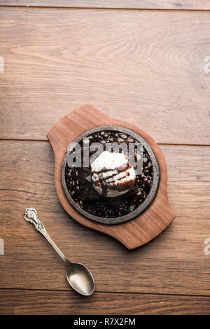 Sizzling Chocolate Brownie ist eine Süßspeise, die mit Kugel Eis-Creme auf der Oberseite mit einem großzügigen Gießen der geschmolzene Schokolade serviert. Server heiß. wählen Stockfoto