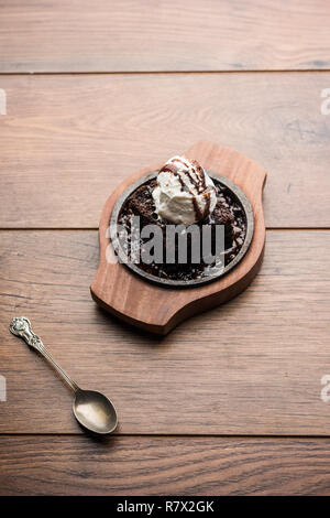 Sizzling Chocolate Brownie ist eine Süßspeise, die mit Kugel Eis-Creme auf der Oberseite mit einem großzügigen Gießen der geschmolzene Schokolade serviert. Server heiß. wählen Stockfoto