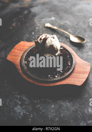 Sizzling Chocolate Brownie ist eine Süßspeise, die mit Kugel Eis-Creme auf der Oberseite mit einem großzügigen Gießen der geschmolzene Schokolade serviert. Server heiß. wählen Stockfoto