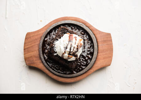 Sizzling Chocolate Brownie ist eine Süßspeise, die mit Kugel Eis-Creme auf der Oberseite mit einem großzügigen Gießen der geschmolzene Schokolade serviert. Server heiß. wählen Stockfoto