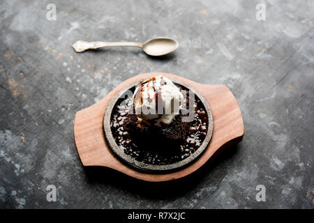 Sizzling Chocolate Brownie ist eine Süßspeise, die mit Kugel Eis-Creme auf der Oberseite mit einem großzügigen Gießen der geschmolzene Schokolade serviert. Server heiß. wählen Stockfoto