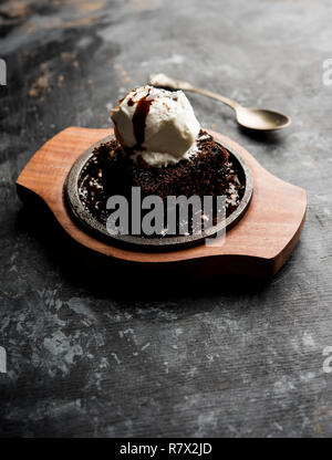 Sizzling Chocolate Brownie ist eine Süßspeise, die mit Kugel Eis-Creme auf der Oberseite mit einem großzügigen Gießen der geschmolzene Schokolade serviert. Server heiß. wählen Stockfoto