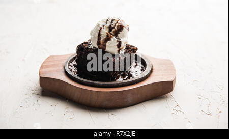 Sizzling Chocolate Brownie ist eine Süßspeise, die mit Kugel Eis-Creme auf der Oberseite mit einem großzügigen Gießen der geschmolzene Schokolade serviert. Server heiß. wählen Stockfoto