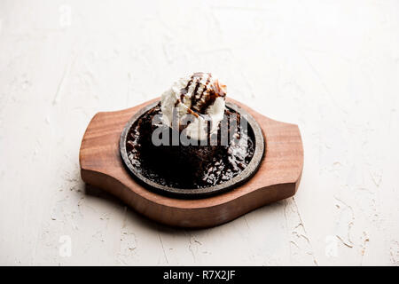 Sizzling Chocolate Brownie ist eine Süßspeise, die mit Kugel Eis-Creme auf der Oberseite mit einem großzügigen Gießen der geschmolzene Schokolade serviert. Server heiß. wählen Stockfoto