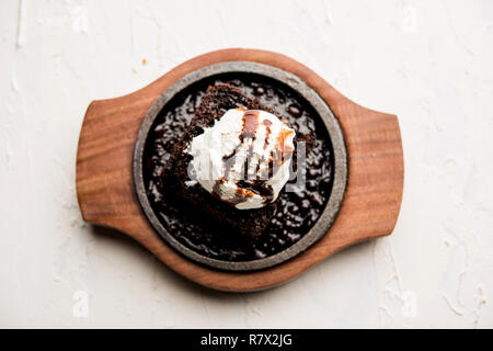 Sizzling Chocolate Brownie ist eine Süßspeise, die mit Kugel Eis-Creme auf der Oberseite mit einem großzügigen Gießen der geschmolzene Schokolade serviert. Server heiß. wählen Stockfoto
