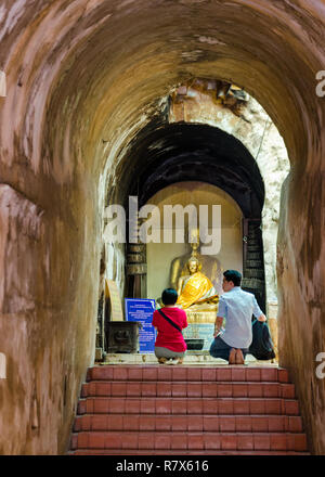 Mann und Frau kniend vor einem vergoldeten Buddha Statue und Beten in Wat Umong's Tunnel, Chiang Mai, Thailand Stockfoto