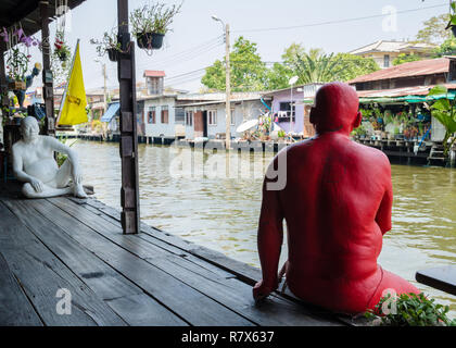 Statuen von Thai Männer lackiert in Rot und Weiß, durch den Fluss Chao Phraya im Baan Silapin Artist's House, Bangkok, Thailand Stockfoto